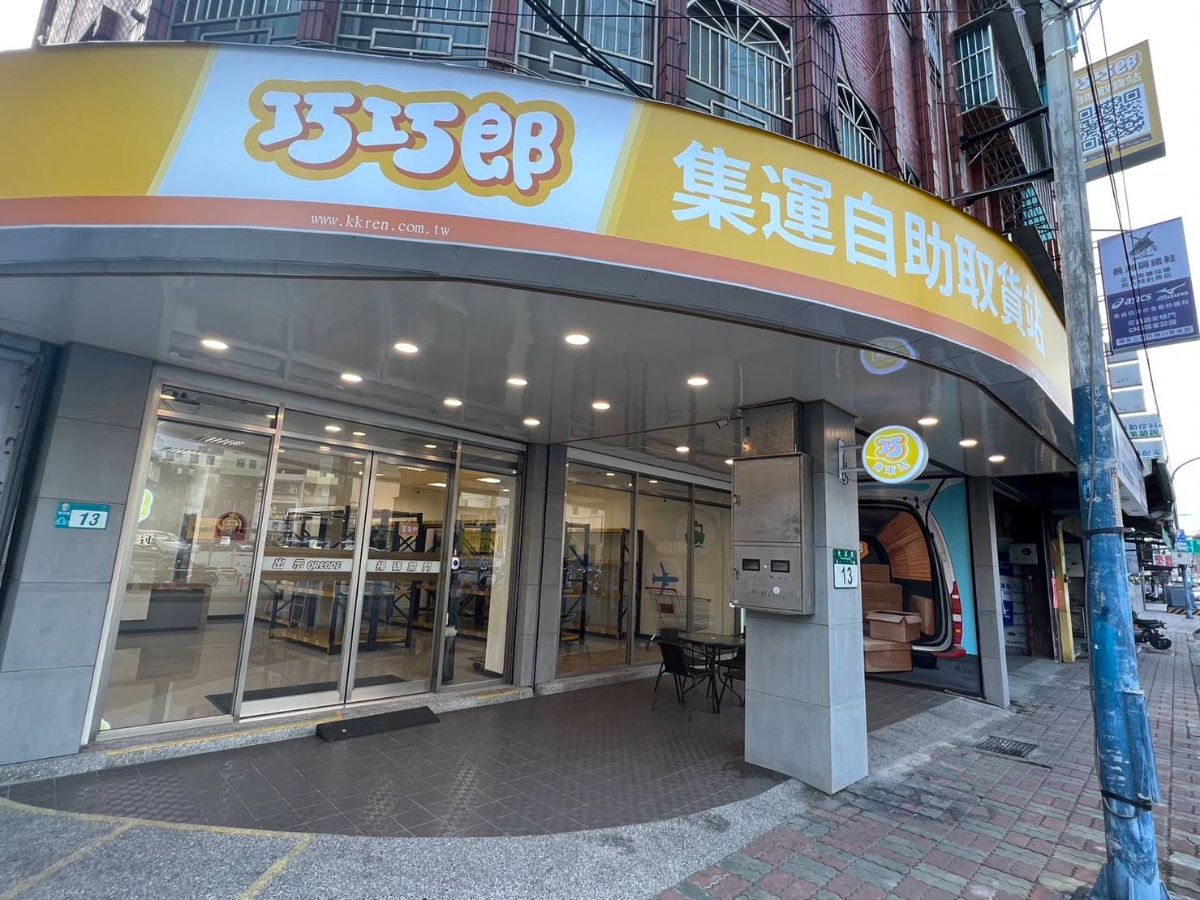 巧巧郎新莊自取店外觀：轉角店面，黃色招牌寫著集運自助取貨站，玻璃門入口與貨架